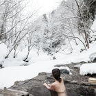 A woman relaxes in a snow covered mountain hot spring onsen resort in Japan.